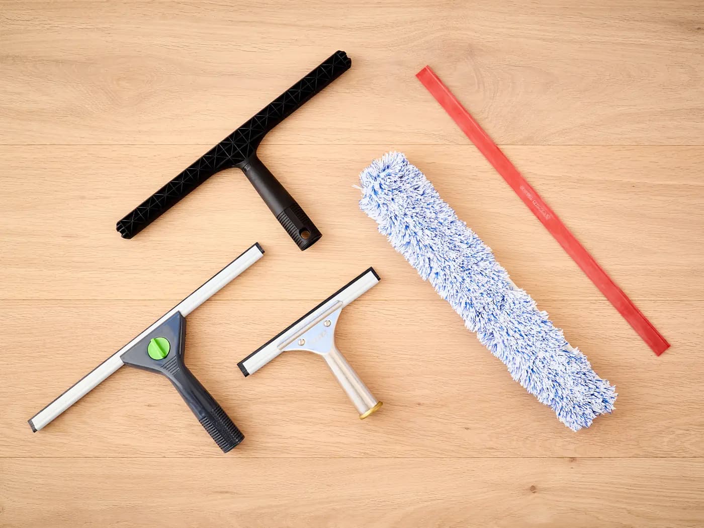 T-bar, two squeegees, a T-bar applicator and a squeegee rubber on a wooden floor