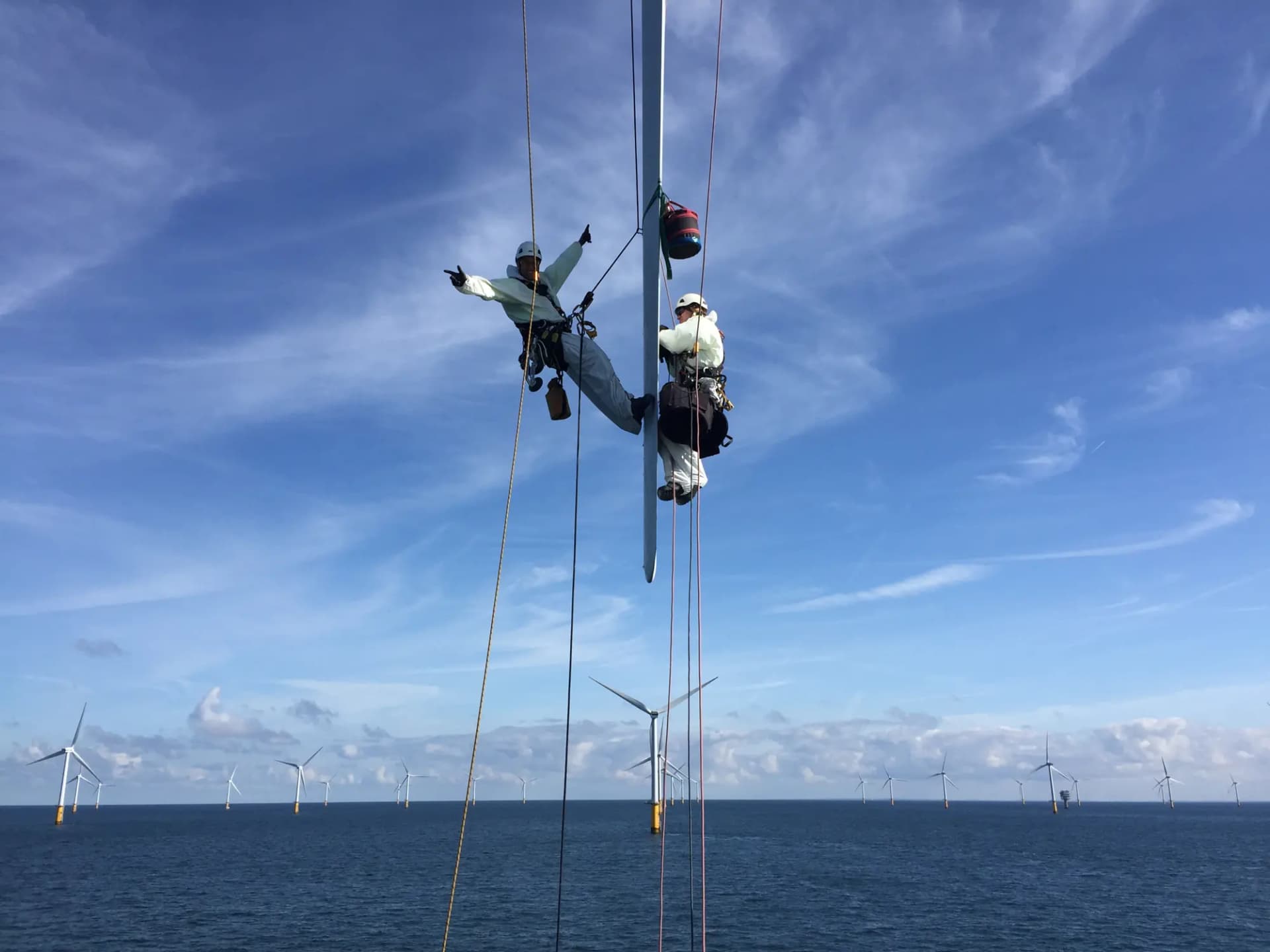 Justin Orloff on rope access, hanging on a wind turbine blade above the open sea