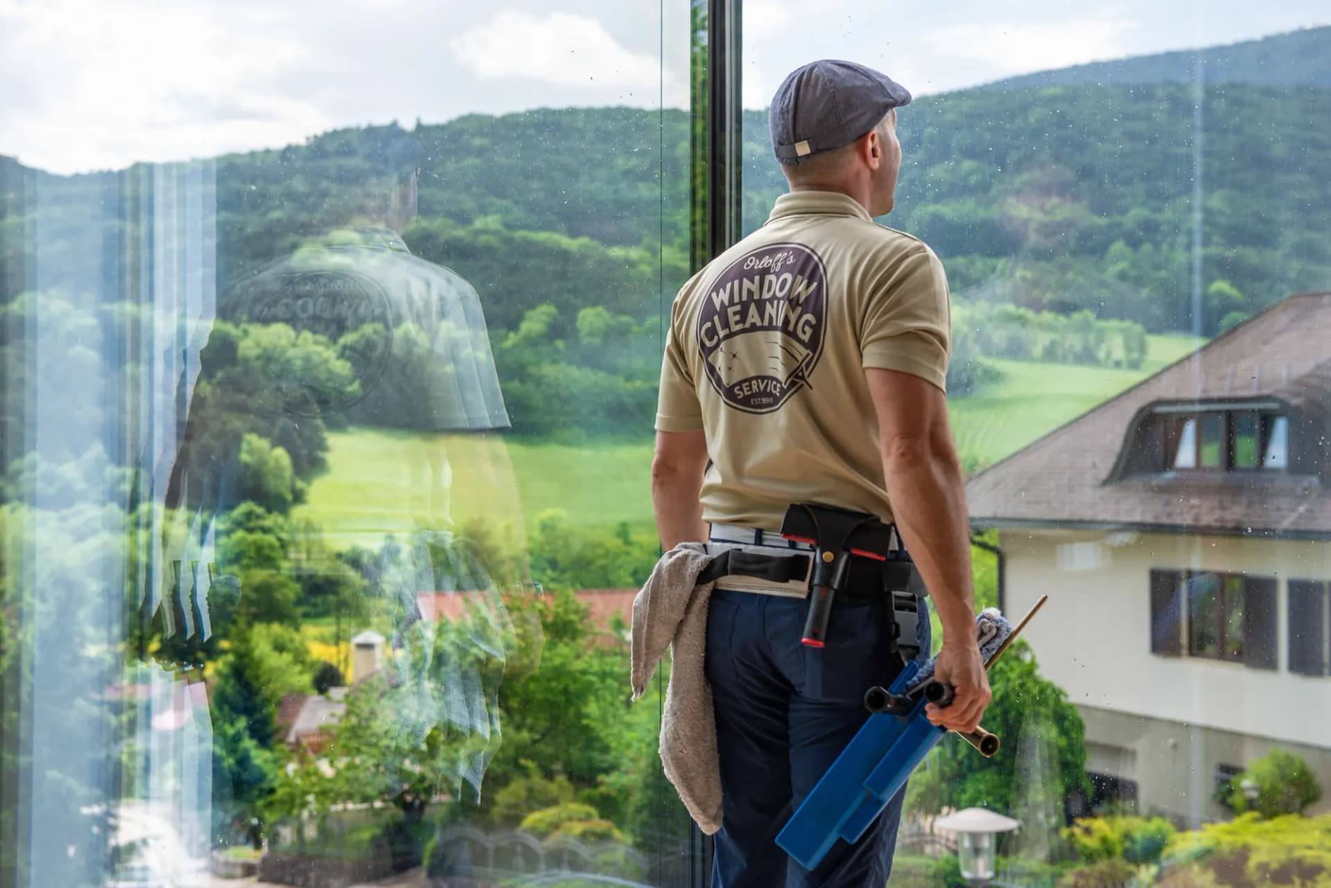 Justin at a floor-to-ceiling window, looking out over a green valley