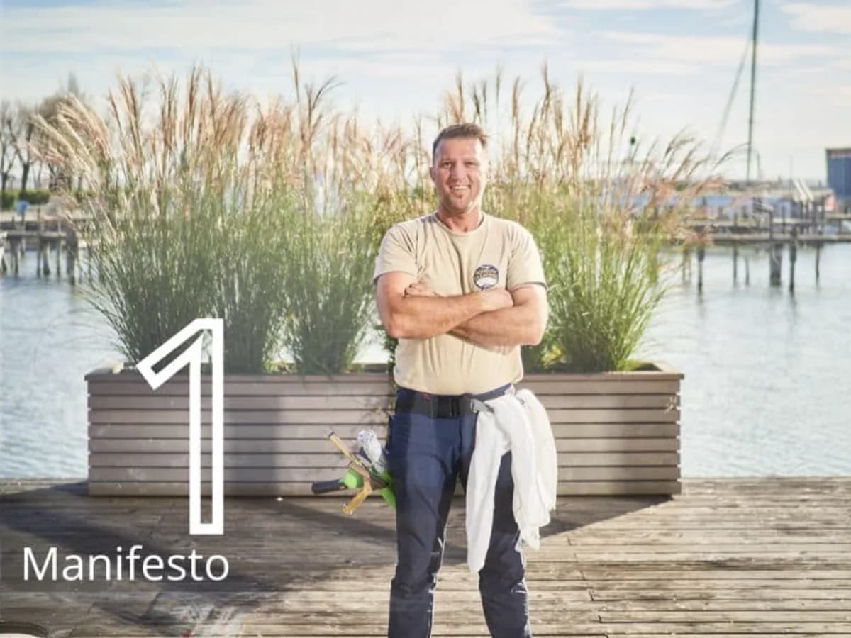 Justin standing by the water next to a large number one and the word Manifesto, the first of the five training steps