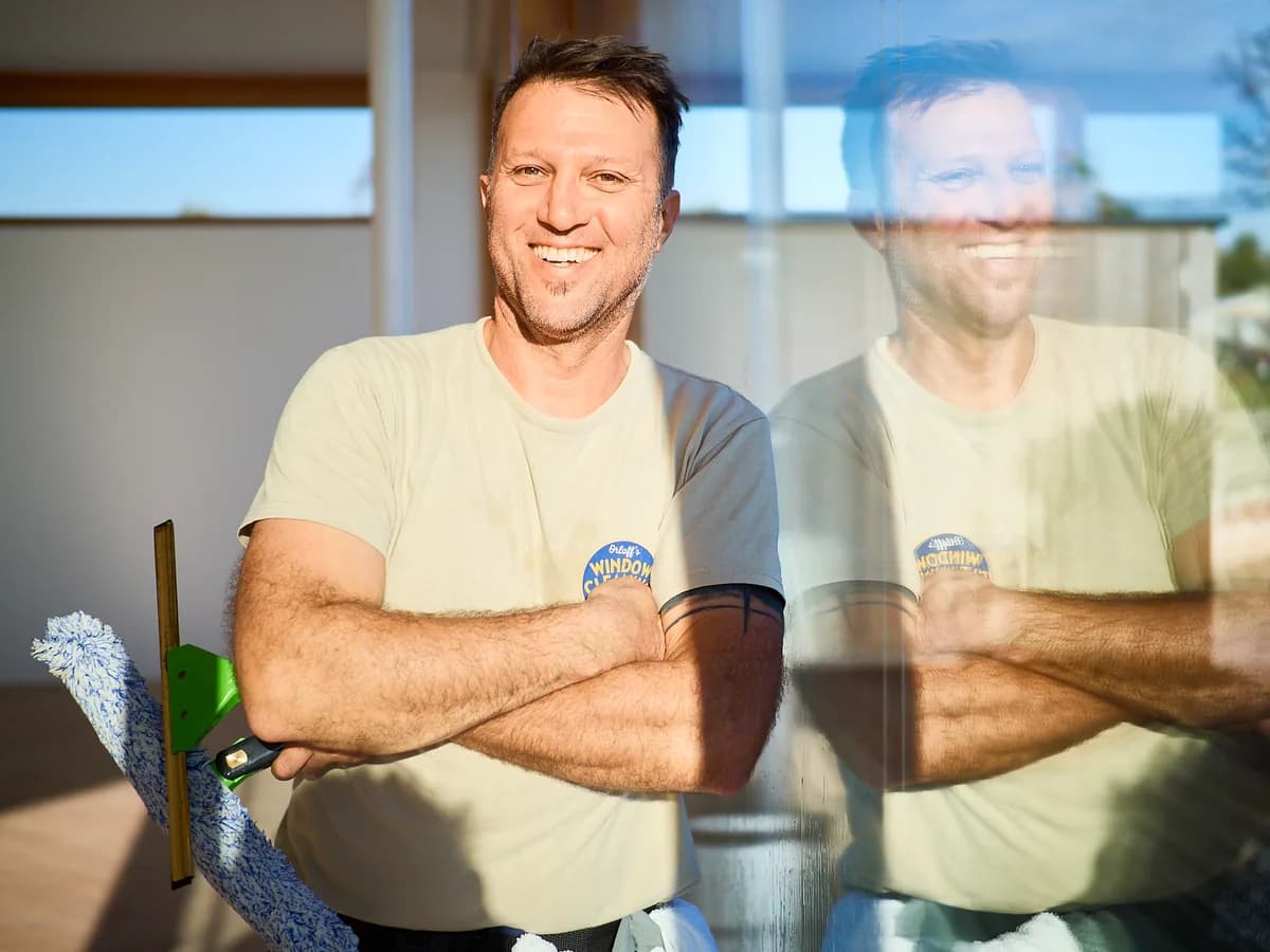 Justin Orloff smiling, arms crossed, next to a clean window