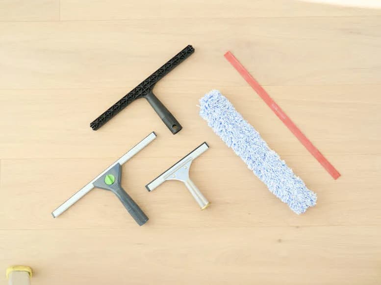 A window cleaning starter kit laid flat: squeegees and a T-bar applicator