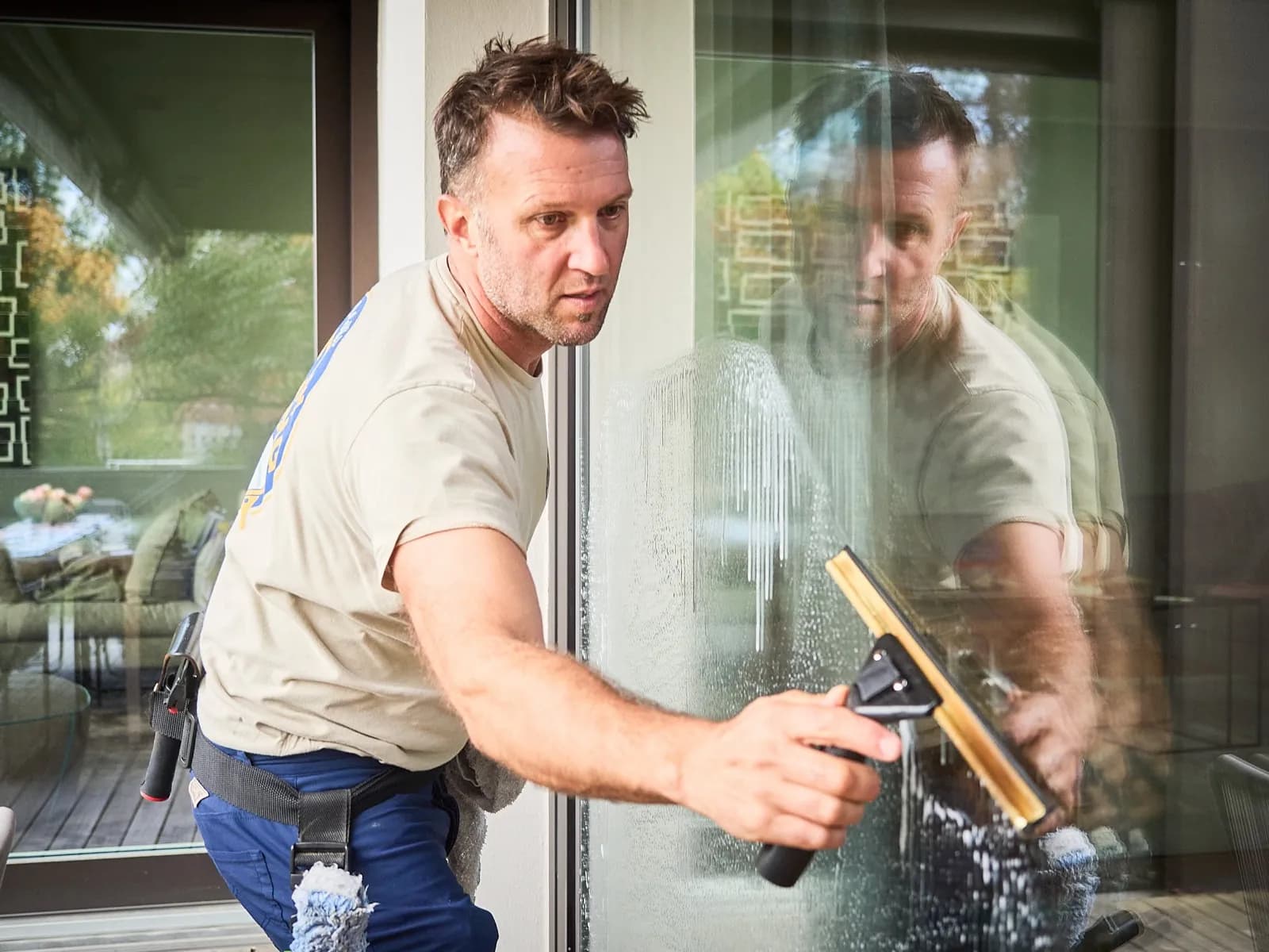 Justin pulling a squeegee down a soapy glass door
